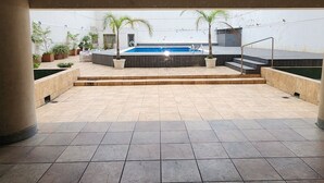 An outdoor patio area with a swimming pool, steps leading to a deck, and potted plants. - Three bedrooms with parking and security. (Buenos Aires)
