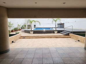 An outdoor patio area with a swimming pool, steps leading to a deck, and potted plants. - Three bedrooms with parking and security. (Buenos Aires)