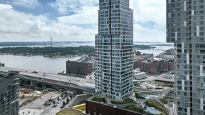 A high-rise building with a modern architectural design, surrounded by a river and a bridge in the background. - Kalasatama apartments by Come in (Helsinki)