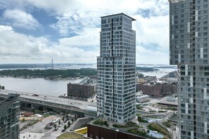 Korkea kerrostalo, jossa on moderni arkkitehtoninen ilme, ja sen ympärillä virtaa joki. Taustalla näkyy silta.