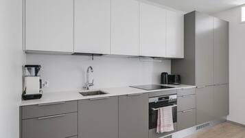 Una cocina moderna con horno empotrado, cafetera y hervidor.