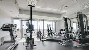Un gimnasio con máquinas de cardio, pesas libres y una prensa de pesas.
