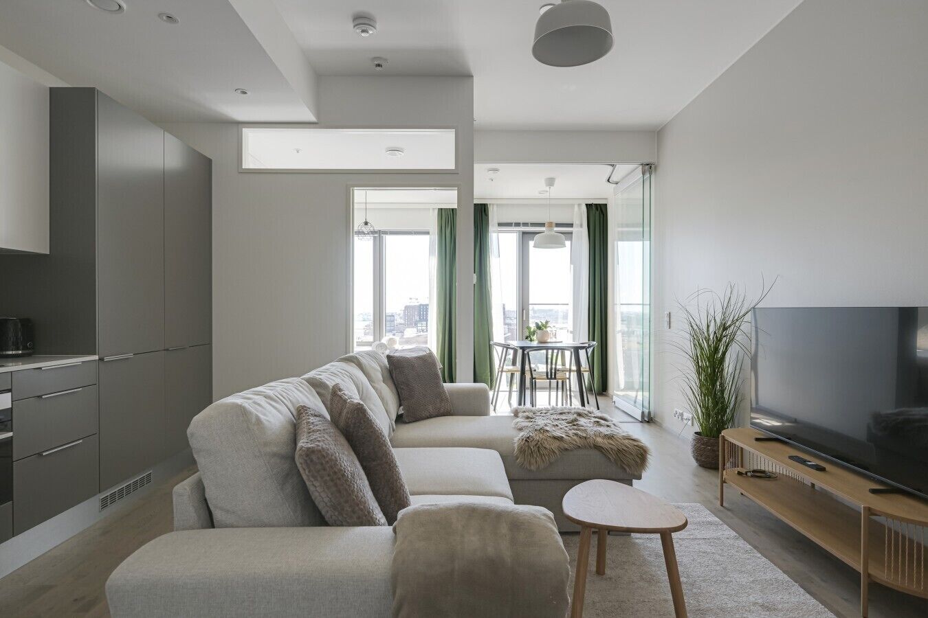 Uma sala de estar moderna com sofá, televisão e área de jantar com mesa e cadeiras.