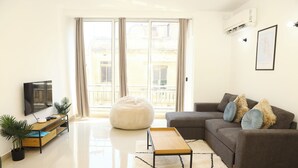 En moderne stue med sofa, skammel og et fladskærms-tv.