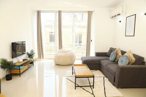 A modern living room with a sofa, ottoman, and a flat-screen TV. - St. Julian's Central Apartment 2 (St. Julian's)