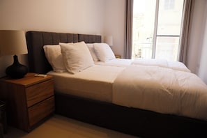 A hotel room with a bed, a nightstand, a lamp, and a window with curtains. - St. Julian's Central Apartment 2 (St. Julian's)