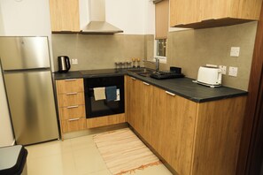 A compact kitchen with a refrigerator, stove, and a coffee maker. - St. Julian's Central Apartment 2 (St. Julian's)