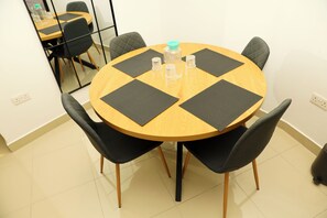 A round table with four chairs, black mats, and clear plastic cups. - St. Julian's Central Apartment 2 (St. Julian's)