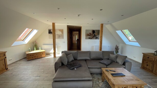 A spacious loft with a large sectional sofa, a wooden coffee table, and a patterned rug. - Ferienwohnung für 4 Personen in Plattenburg (Plattenburg)