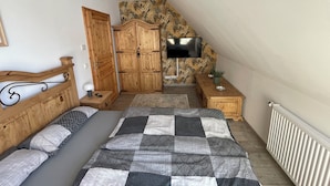 A bedroom with a bed, a wardrobe, a television, and a small table. - Ferienwohnung für 4 Personen in Plattenburg (Plattenburg)