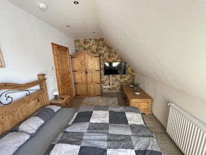 A bedroom with a bed, a wardrobe, a television, and a small table. - Ferienwohnung für 4 Personen in Plattenburg (Plattenburg)