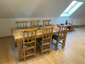 A dining area with a wooden table and chairs, a skylight, and a radiator. - Ferienwohnung für 4 Personen in Plattenburg (Plattenburg)