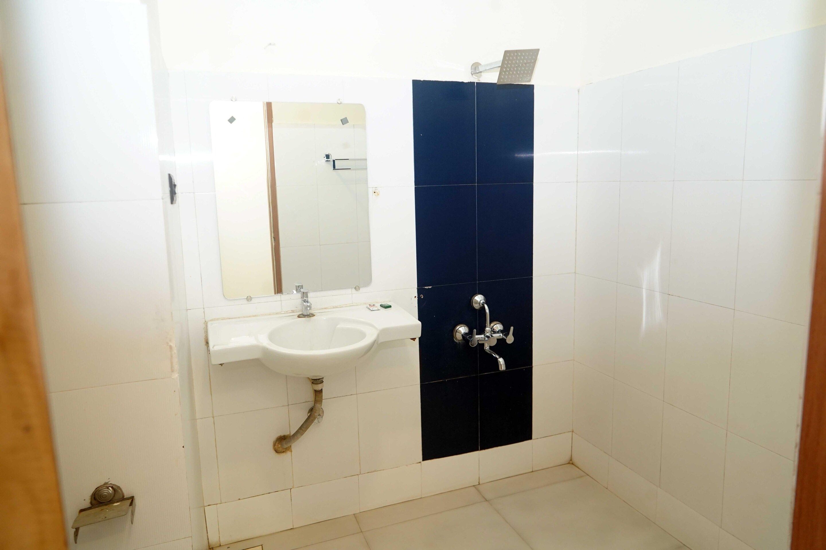 Un baño con lavamanos blanco, un espejo y una ducha con pared azul oscuro.