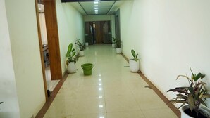 A hallway with potted plants, a green bucket, and a wooden door.