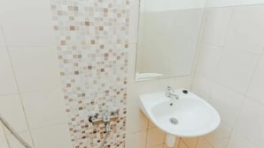 Un baño con pared de ducha con azulejos, un lavabo y un espejo.