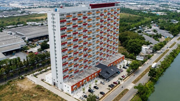 Un hotel de gran altura con varios pisos, un estacionamiento y un río junto al edificio.