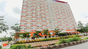 Un hotel de varios pisos con fachada uniforme, balcones y un jardín delantero ajardinado.