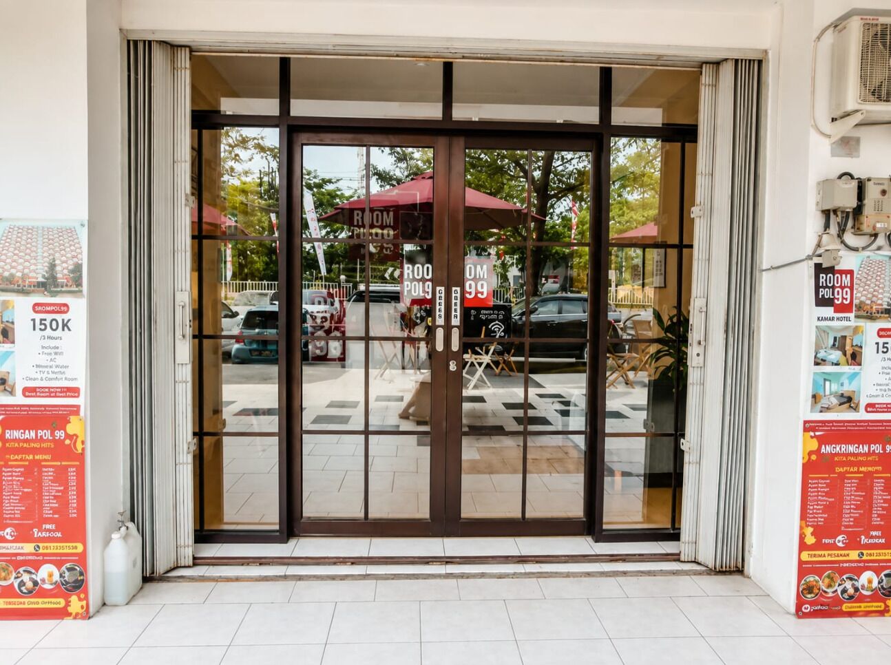 A hotel entrance with a glass door, a sign indicating room rates, and a view of the street outside.