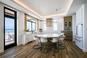 A modern kitchen with a central island, white cabinetry, and a view of the ocean. - Gulf Front with Panoramic Views & Elevator- Da Beach by Royal Destinations (Santa Rosa Beach)