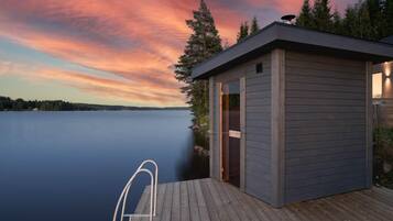 Un moll de fusta amb una escala metàl·lica que condueix a una petita cabana al costat d'un llac tranquil al capvespre.