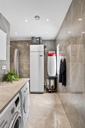 A modern bathroom with a built-in washing machine, a water heater, and a towel rack.