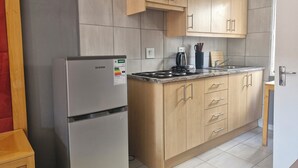 Una cocina compacta con refrigerador, estufa y armarios de madera.