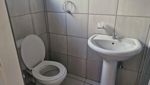 Un baño con inodoro y lavamanos sobre pedestal.