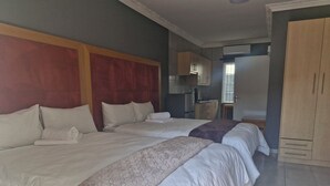 Habitación de hotel con dos camas, una kitchenette y un armario.