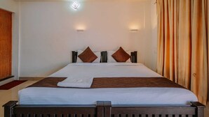 A hotel room with a large bed, two wall-mounted lights, and a curtain on the right side. - Chaithanya Residency  (Kochi)