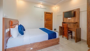 A hotel room with a bed, a desk, a television, and a wooden door. - Chaithanya Residency  (Kochi)