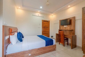 A hotel room with a bed, a desk, a television, and a wooden door. - Chaithanya Residency  (Kochi)