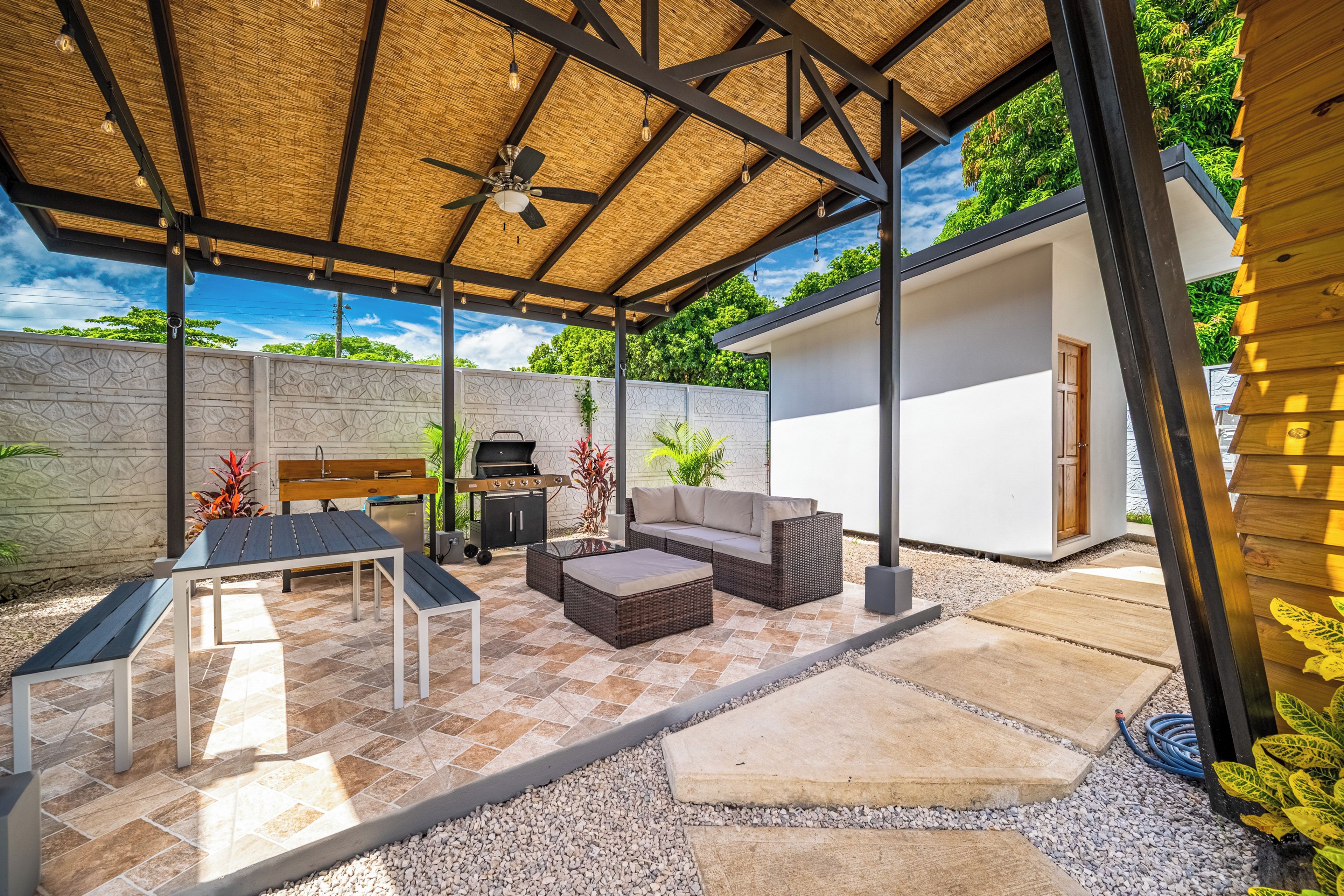 Een terras buiten met een tafel, stoelen, een bank en een barbecue.