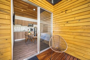 Eine moderne Küche mit Holzschnitzereien, ein Essbereich mit Tisch und Stühlen sowie eine Schiebetür zu einem Schlafzimmer mit einem Bett.