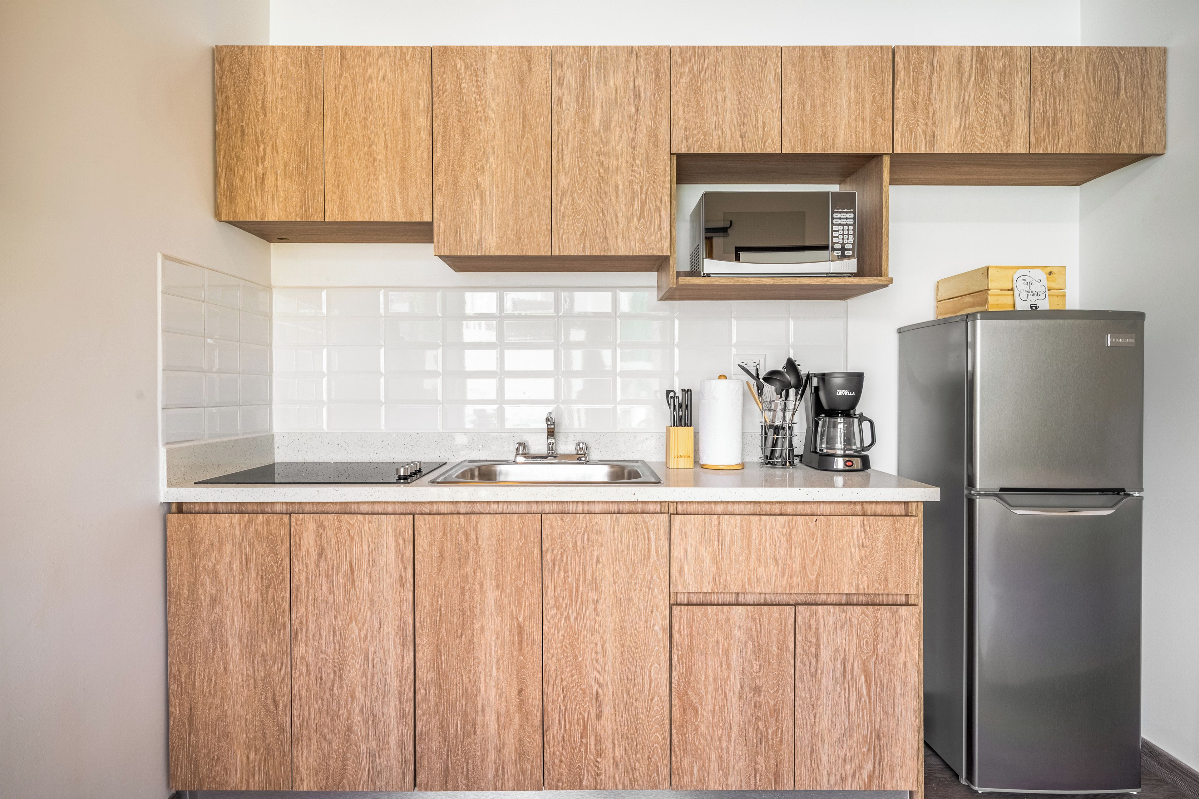 A kitchen with wooden cabinets, a stainless steel refrigerator, a microwave, and a coffee maker.
