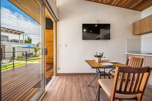 Eine moderne Küche mit Flachbildfernseher, Holzboden und einem Essbereich mit Tisch und Stühlen.