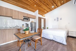 A modern kitchen with wooden cabinets, a dining table with chairs, a refrigerator, and a bed with a white bedspread. - Private 2-studio Retreat Near Playa Del Coco! (Sardinal)