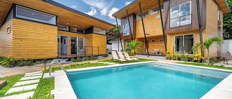 A modern two-story house with a swimming pool, wooden exterior, and a covered patio area.