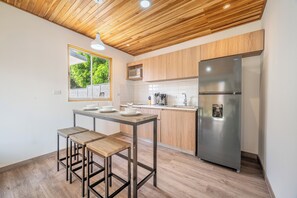 Eine moderne Küche mit Holzboden, einem Edelstahlkühlschrank und einer Essecke mit Hockern.