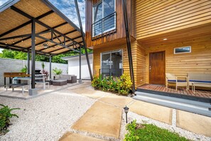 A modern outdoor patio with a barbecue, seating, and a wooden deck. - Chic 'alpinias' Condo w/ Pool Access, Near Beach (Sardinal)