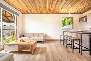 Eine moderne Küche mit Holzboden, ein Essbereich mit einer Couch und Blick auf Grünfläche.
