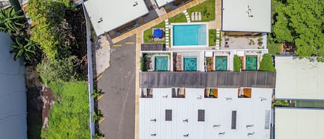 A multi-story building with a rooftop pool, multiple balconies, and a parking area.