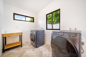 A laundry room with two washing machines, a sink, and a window with a view of greenery. - Walk to Shops & Eats! Cozy Playas Del Coco Studio (Sardinal)