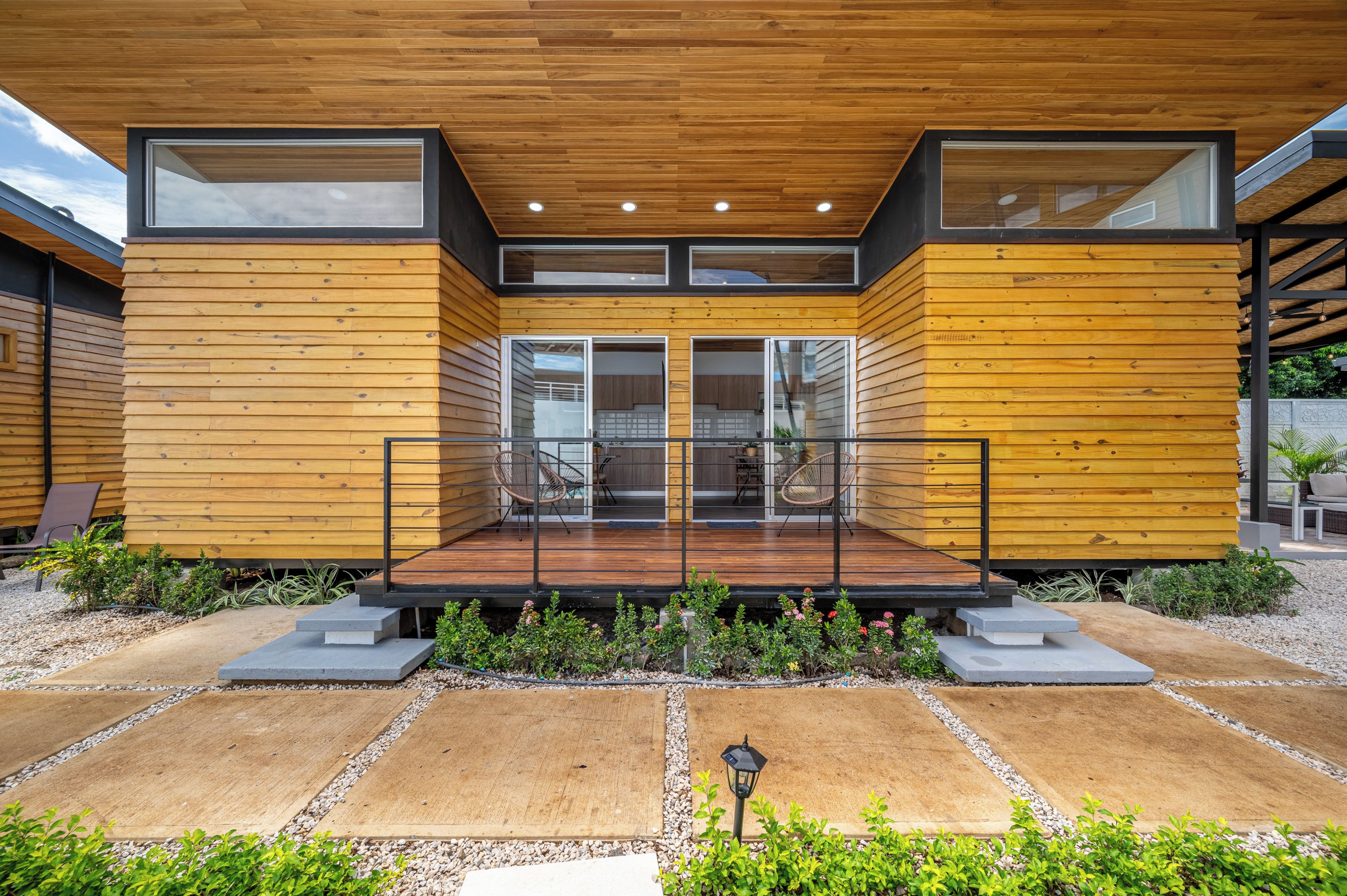 Een modern huis met een houten gevel, grote glazen deuren en een overdekt terras.