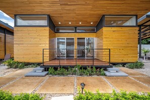Uma casa moderna com fachada de madeira, grandes portas de vidro e área de estar coberta ao ar livre.
