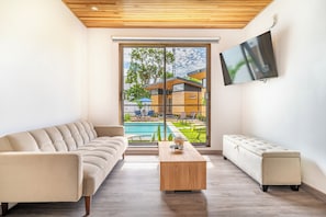 A modern living room with a sofa, a coffee table, and a TV on the wall. - 'veranera' Condo w/ Pool Access, 1/2 Mi to Beach! (Sardinal)