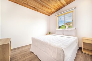 A bedroom with a wooden ceiling, a large window, a bed with white bedding, and a small bedside table with a plant. - 'veranera' Condo w/ Pool Access, 1/2 Mi to Beach! (Sardinal)