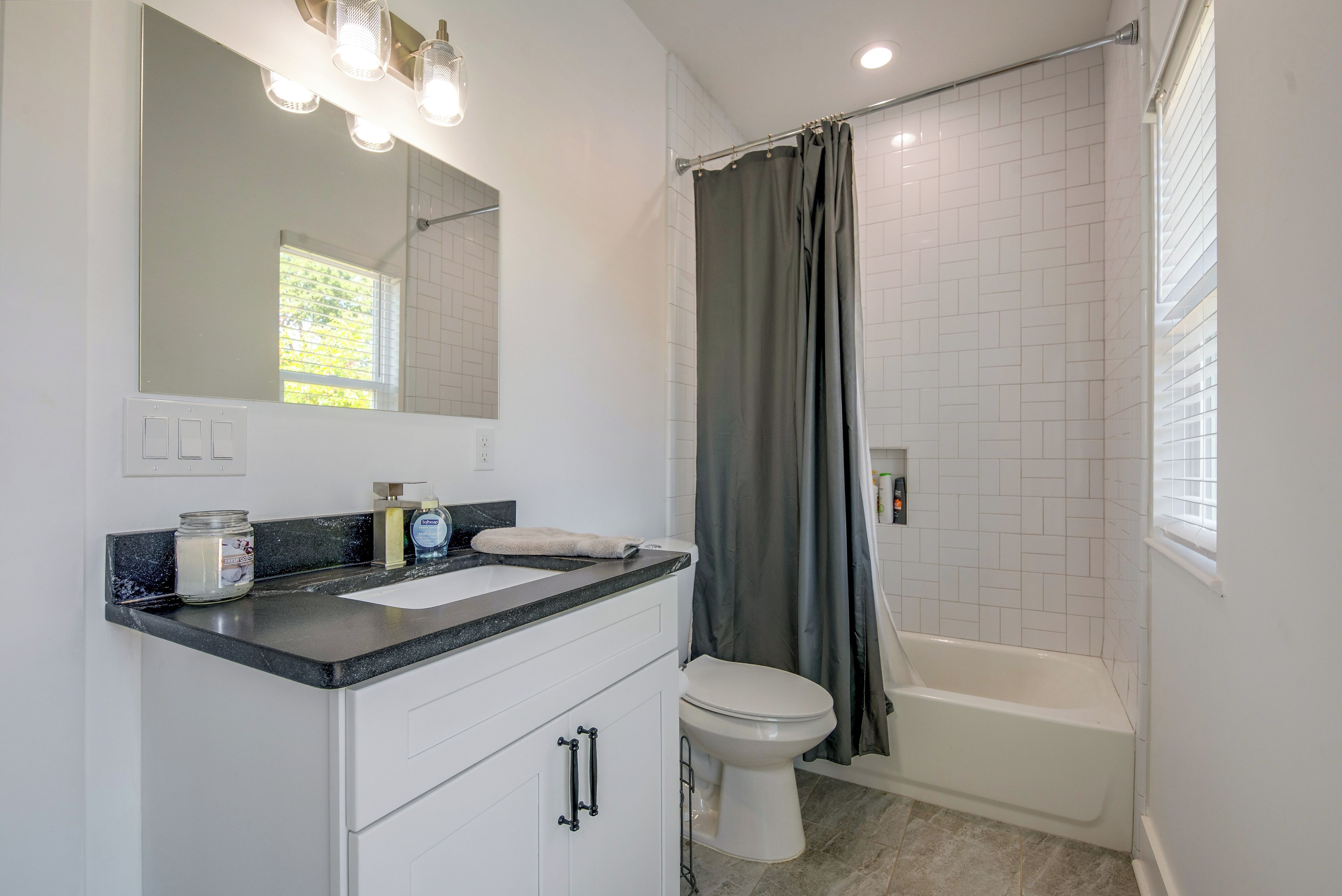Une salle de bain avec des toilettes blanches, un lavabo avec un miroir au-dessus et un rideau de douche.