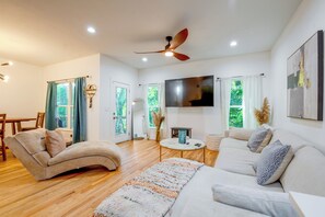 A modern living room with a sofa, a coffee table, and a TV mounted on the wall. - Upper Westside Home w/ Chef's Kitchen & Deck (Atlanta)