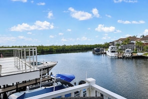 A marina with boats docked, a dock with a covered area, and houses in the background. - Cape Harbour Getaway! Fantastic View & Location (Cape Coral)