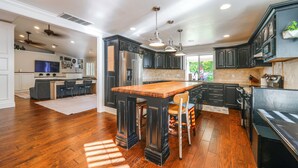 A modern kitchen with dark cabinetry, a wooden island, and pendant lighting.
